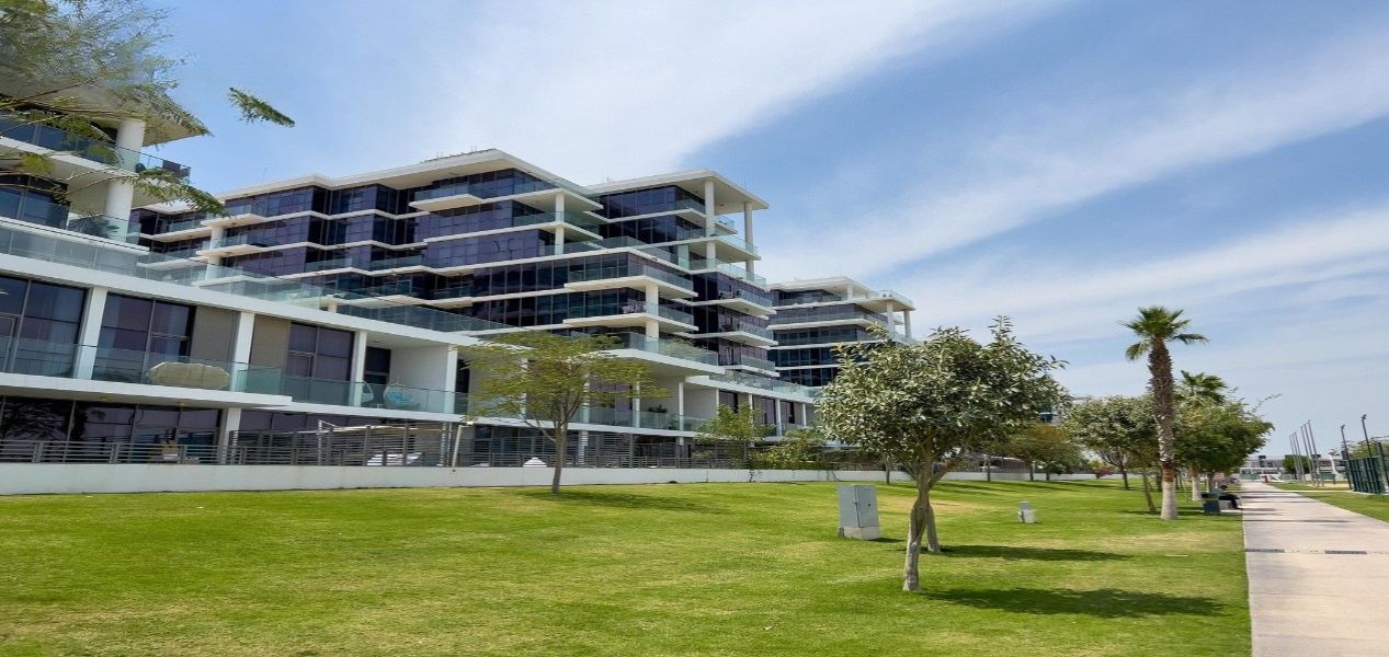 2‑bedroom Golf Greens apartment exterior with landscaped lawn and walking path