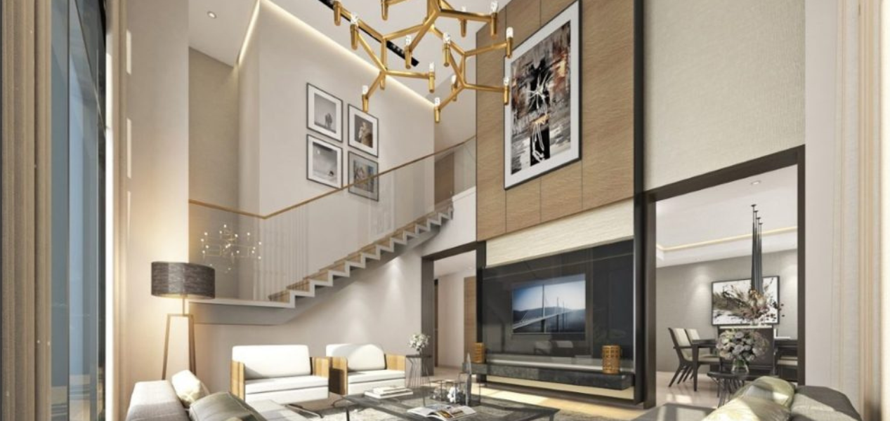Double-height luxury duplex lounge interior at Skyscape Aura Sobha Hartland featuring statement chandelier and staircase.