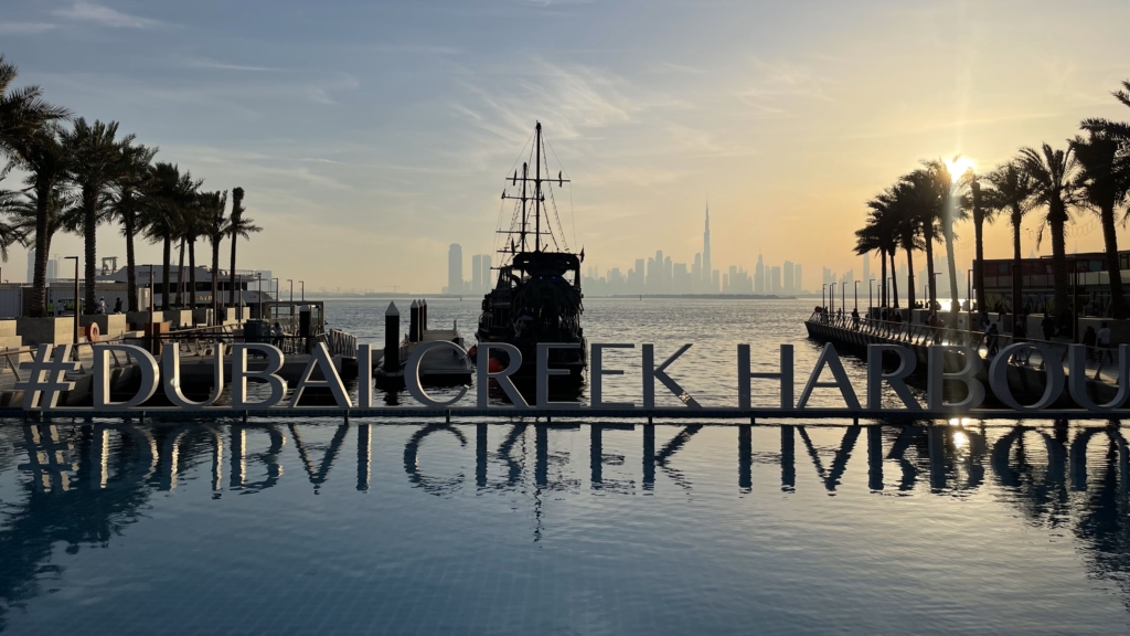 Waterfront view with Dubai Creek Harbour sign at sunset, ideal for investors